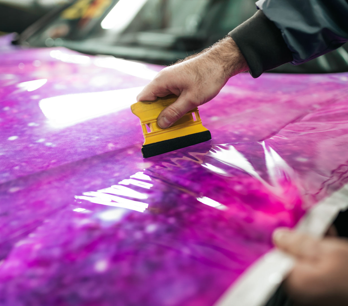 Applying purple car wrap with tool